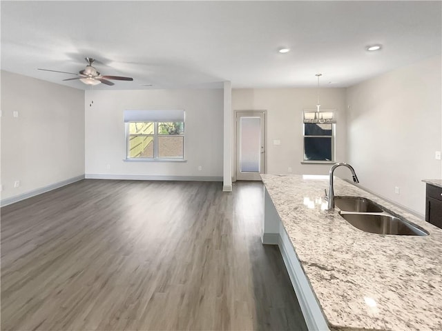 kitchen featuring dark wood-style floors, open floor plan, baseboards, and a sink