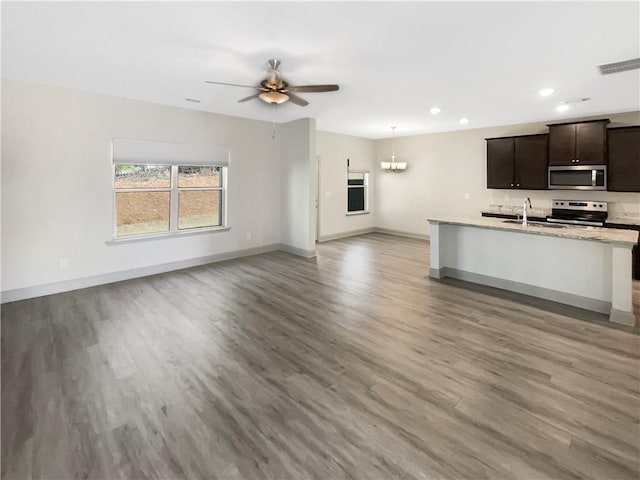 kitchen with wood finished floors, baseboards, a sink, stainless steel appliances, and open floor plan