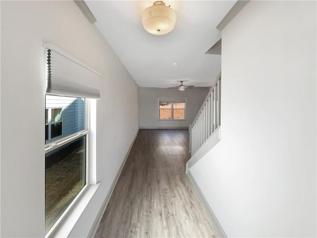 corridor with stairway, baseboards, and wood finished floors