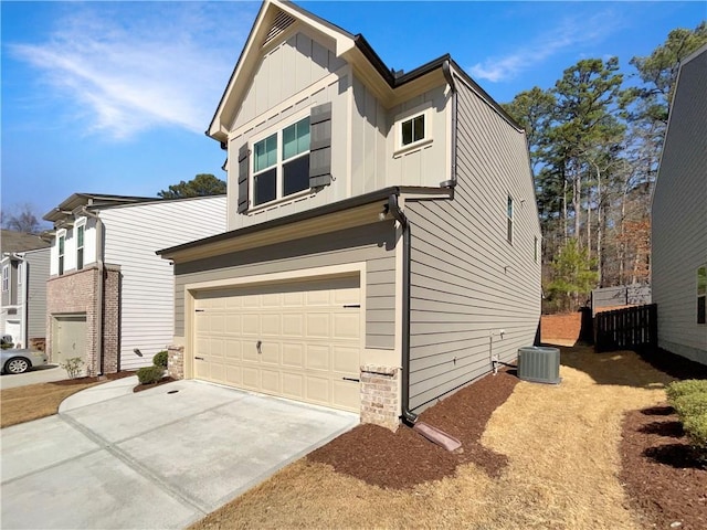 view of side of home featuring a garage, central AC unit, board and batten siding, and driveway