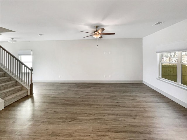 empty room featuring stairs, wood finished floors, visible vents, and baseboards