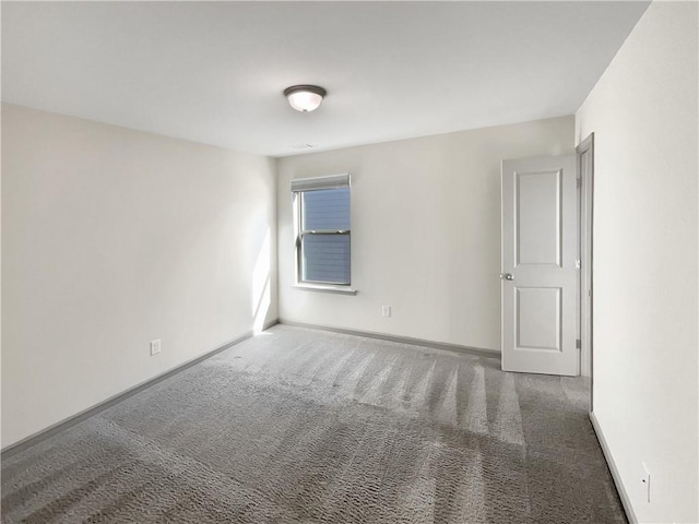 carpeted empty room featuring baseboards