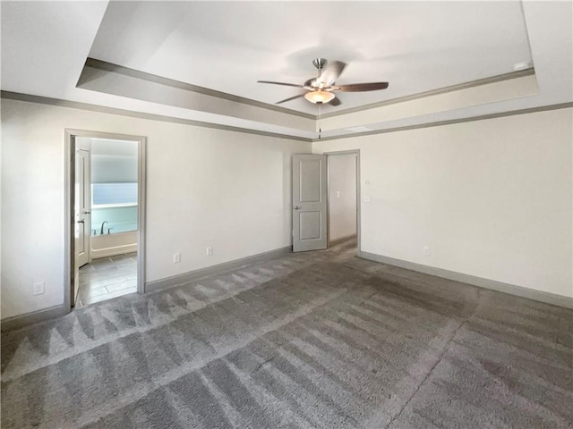 carpeted spare room with a tray ceiling, baseboards, and ceiling fan