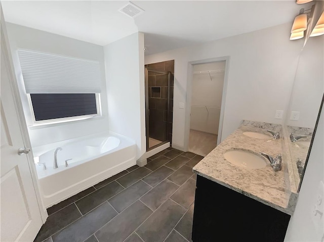 bathroom with visible vents, a walk in closet, a sink, a shower stall, and a bath