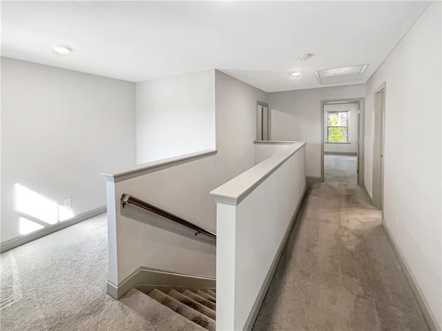 hallway with an upstairs landing, light colored carpet, and baseboards