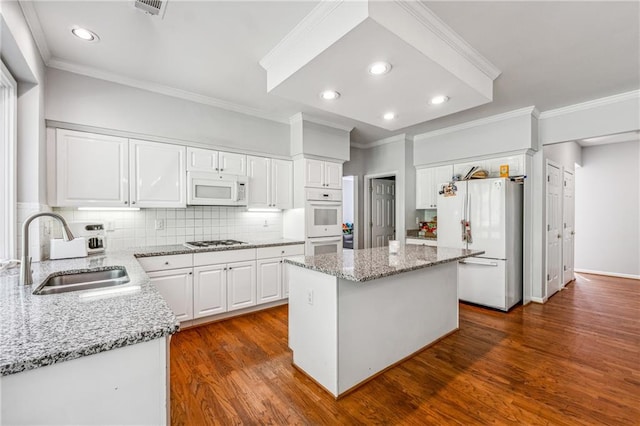 kitchen with dark wood-type flooring, white appliances, a kitchen island, and sink