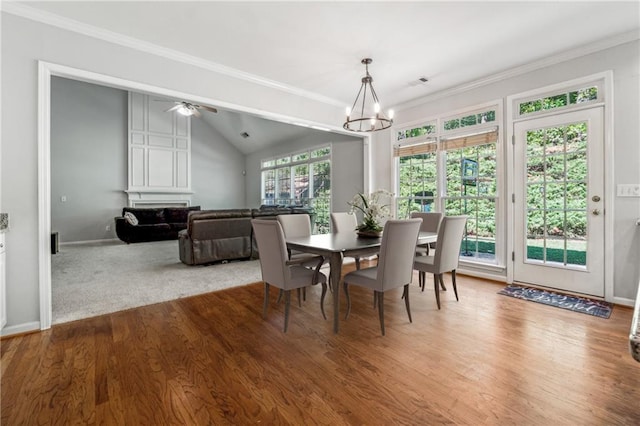 dining area with hardwood / wood-style flooring, ornamental molding, plenty of natural light, and vaulted ceiling