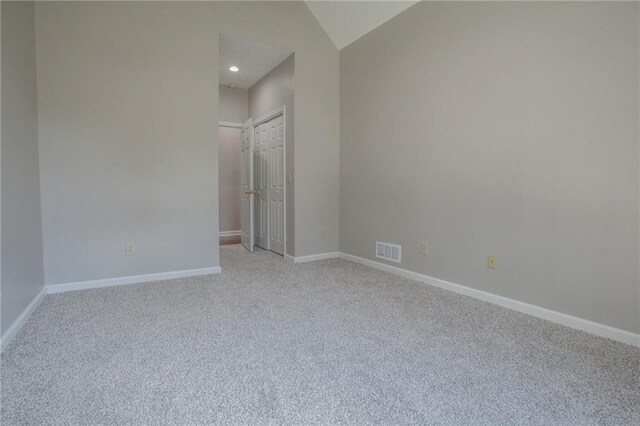 empty room featuring light carpet and vaulted ceiling