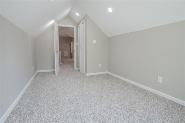 additional living space with light carpet and vaulted ceiling