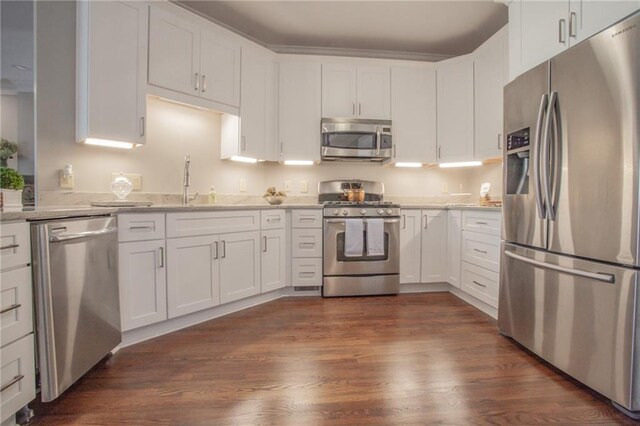 kitchen featuring dark hardwood / wood-style flooring, appliances with stainless steel finishes, sink, white cabinetry, and light stone counters