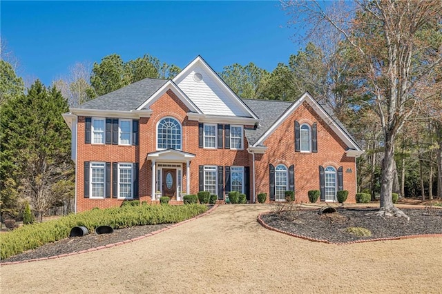 colonial house featuring brick siding and driveway