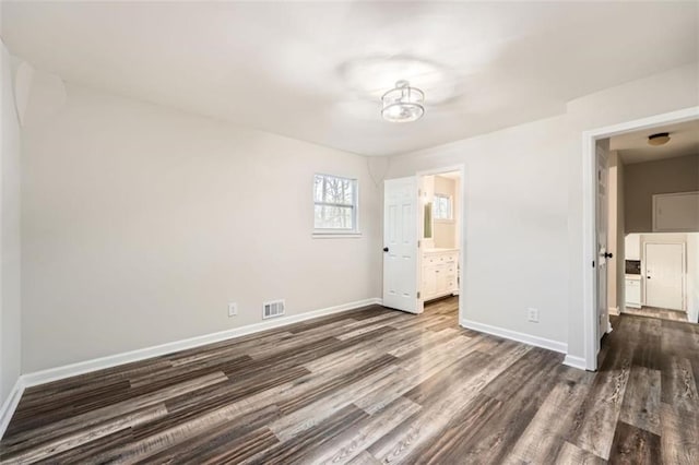 unfurnished bedroom featuring connected bathroom and dark hardwood / wood-style floors