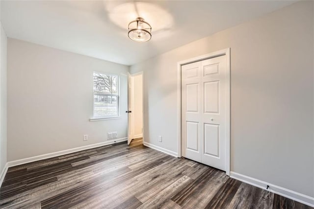 unfurnished bedroom featuring dark wood-type flooring and a closet