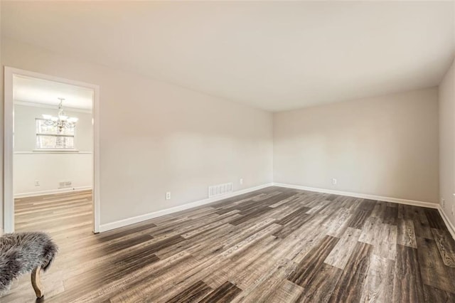 unfurnished room with an inviting chandelier and dark hardwood / wood-style floors