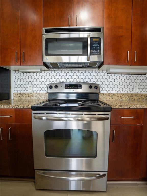 kitchen featuring light stone counters, backsplash, and appliances with stainless steel finishes