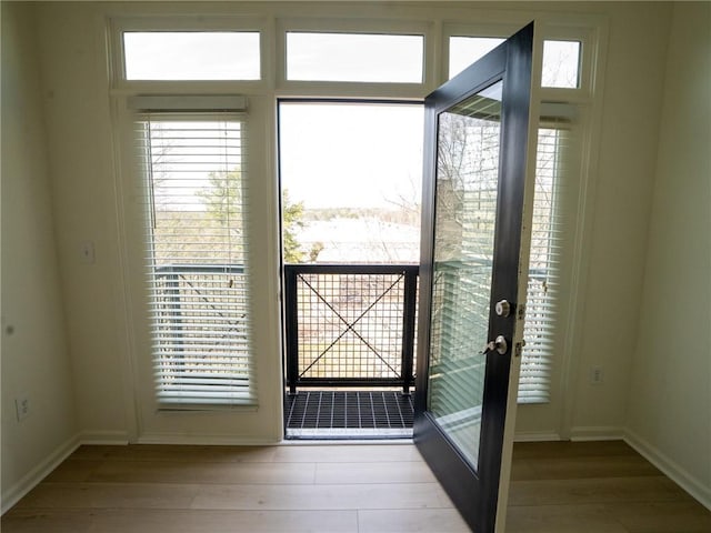 doorway with wood finished floors and baseboards