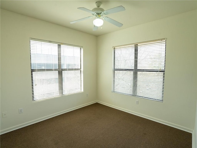 unfurnished room featuring baseboards, dark carpet, and ceiling fan