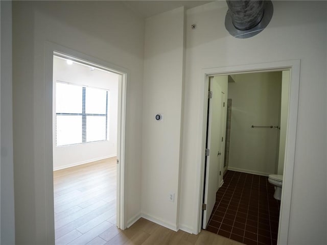 corridor featuring baseboards and light wood-style floors