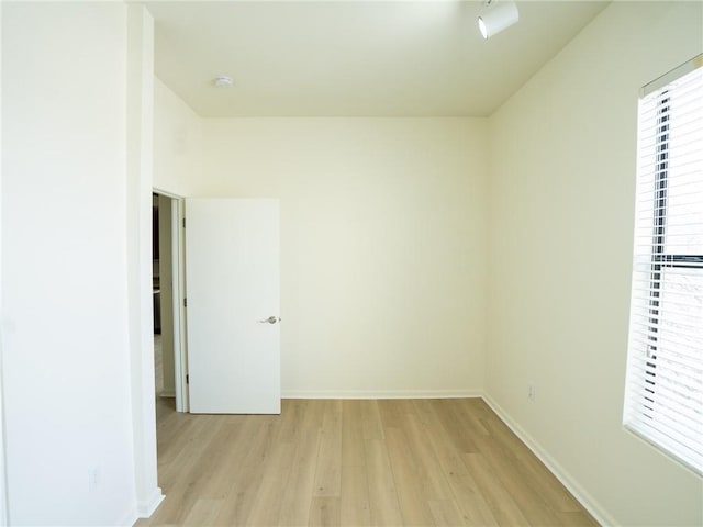 spare room featuring baseboards, plenty of natural light, and light wood-style floors