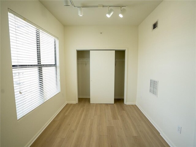 unfurnished bedroom with a closet, baseboards, visible vents, and light wood finished floors