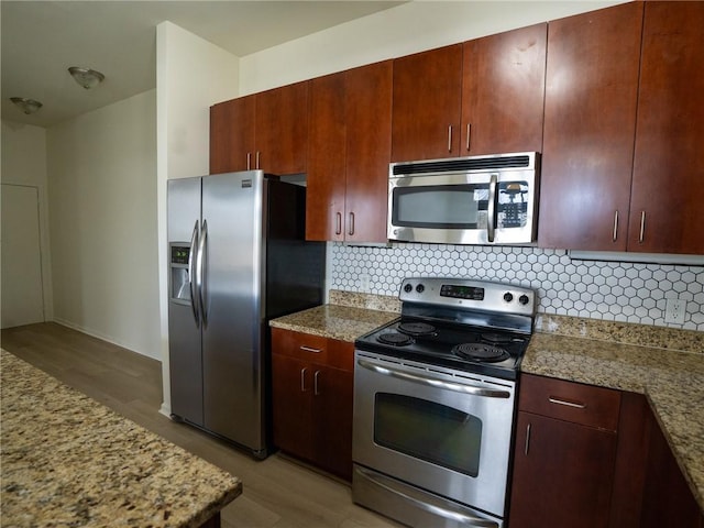 kitchen with backsplash, appliances with stainless steel finishes, light wood-style flooring, and light stone countertops