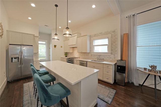 kitchen with a breakfast bar, dark wood-style floors, light countertops, appliances with stainless steel finishes, and backsplash