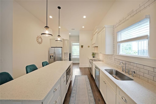 kitchen featuring dark wood-style flooring, a large island, a sink, appliances with stainless steel finishes, and a wealth of natural light