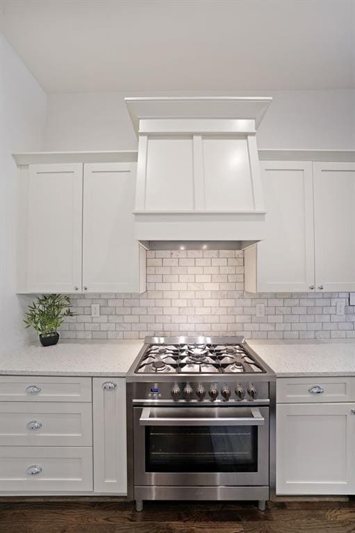 kitchen featuring white cabinets, backsplash, custom range hood, and high end range