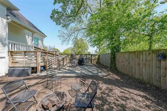 view of yard featuring a fenced backyard, a patio, a fire pit, and a deck