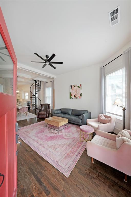 living area featuring visible vents, a ceiling fan, plenty of natural light, and wood finished floors