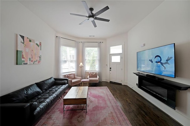 living area with a ceiling fan, baseboards, visible vents, and wood finished floors