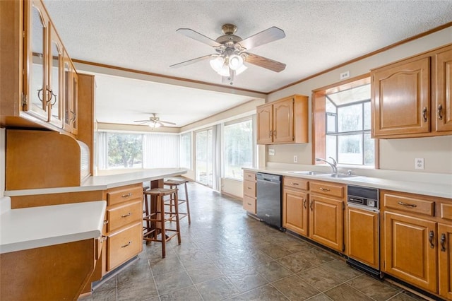 kitchen featuring a breakfast bar area, stainless steel dishwasher, sink, and a wealth of natural light