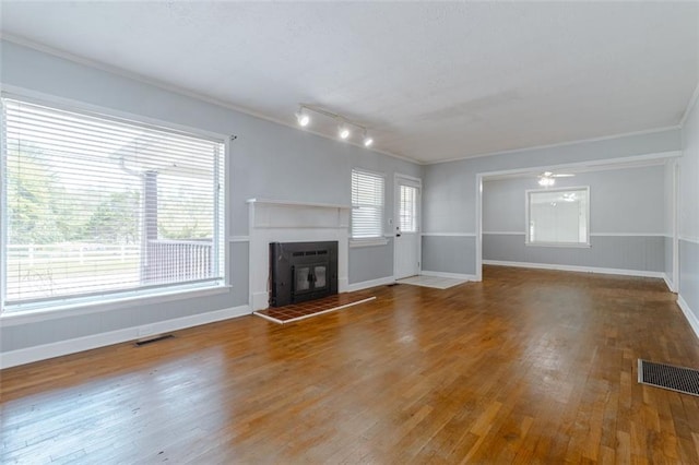 unfurnished living room featuring hardwood / wood-style flooring, crown molding, and a wealth of natural light