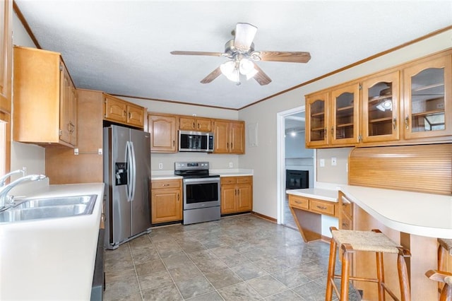 kitchen featuring a breakfast bar, sink, appliances with stainless steel finishes, crown molding, and ceiling fan