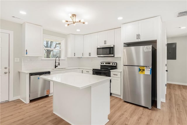 kitchen featuring appliances with stainless steel finishes, sink, light hardwood / wood-style flooring, white cabinets, and a kitchen island