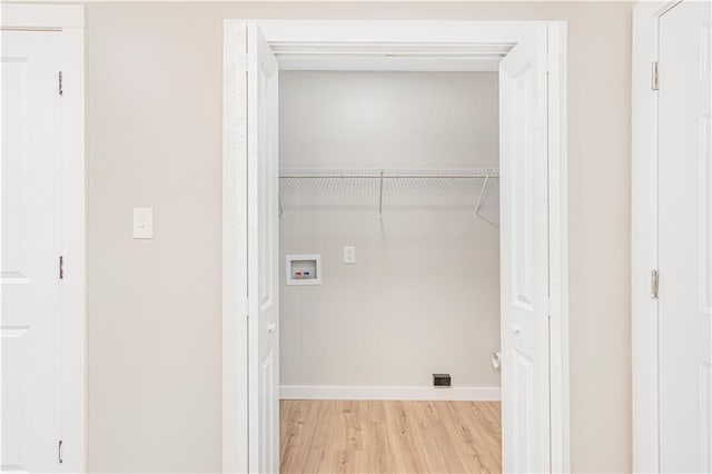 clothes washing area with hookup for a washing machine and light hardwood / wood-style flooring