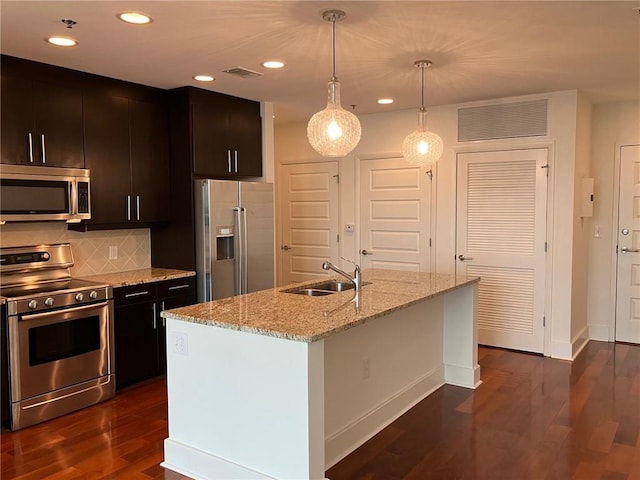 kitchen with sink, decorative light fixtures, appliances with stainless steel finishes, dark hardwood / wood-style floors, and a kitchen island with sink