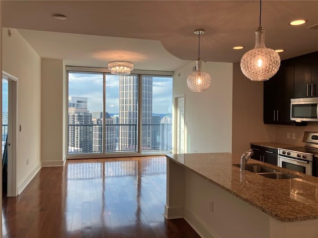 kitchen with pendant lighting, dark wood-type flooring, stainless steel appliances, light stone countertops, and expansive windows