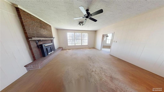 unfurnished living room with a textured ceiling, ceiling fan, carpet floors, and a fireplace