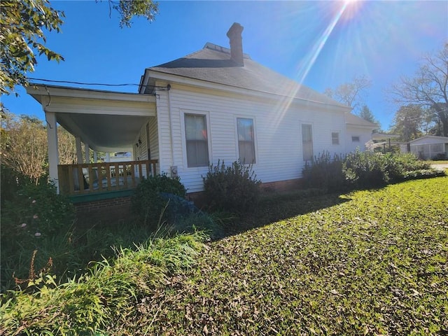 view of side of property with covered porch and a yard