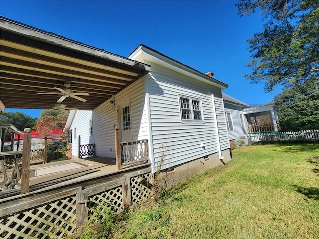 view of side of home with a lawn, ceiling fan, and a deck