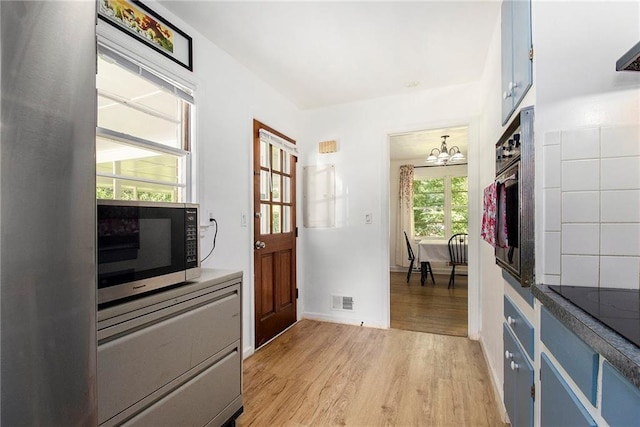 3055 Henderson Mill Rd, Atlanta, GA 30341 - kitchen featuring blue cabinets, light wood finished floors, a chandelier, wall oven, and baseboards