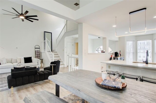 dining space with ceiling fan, sink, a high ceiling, and light wood-type flooring