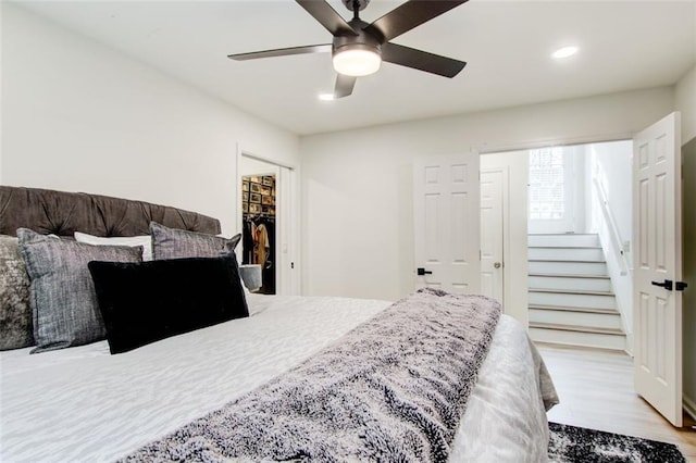 bedroom featuring a closet, ceiling fan, light hardwood / wood-style flooring, and a walk in closet