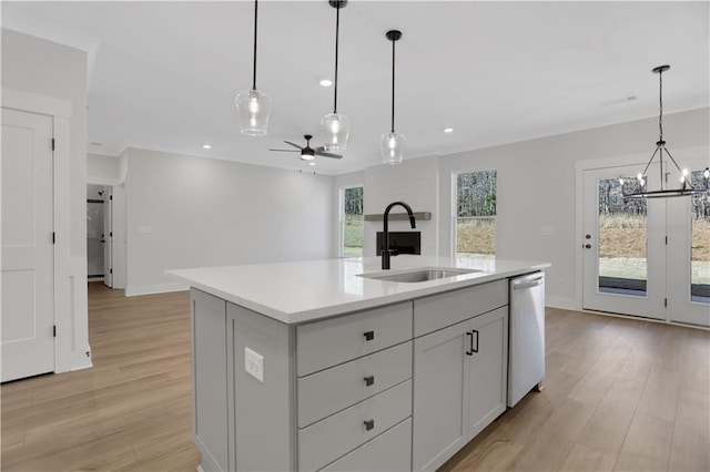 kitchen with sink, dishwasher, ceiling fan with notable chandelier, a center island with sink, and pendant lighting