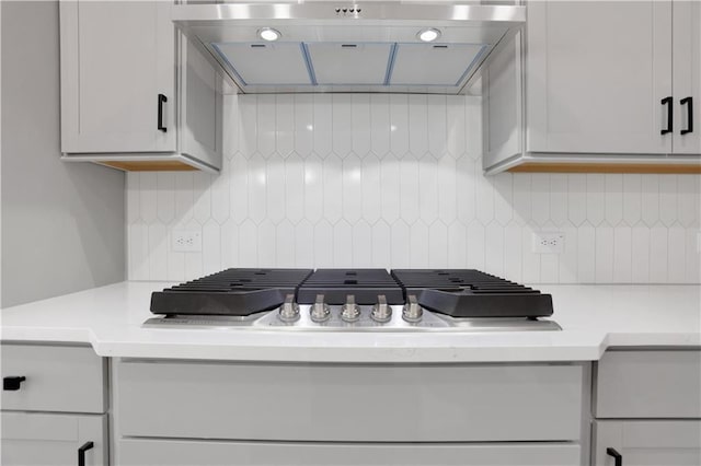 kitchen featuring white cabinets, stainless steel gas stovetop, and backsplash