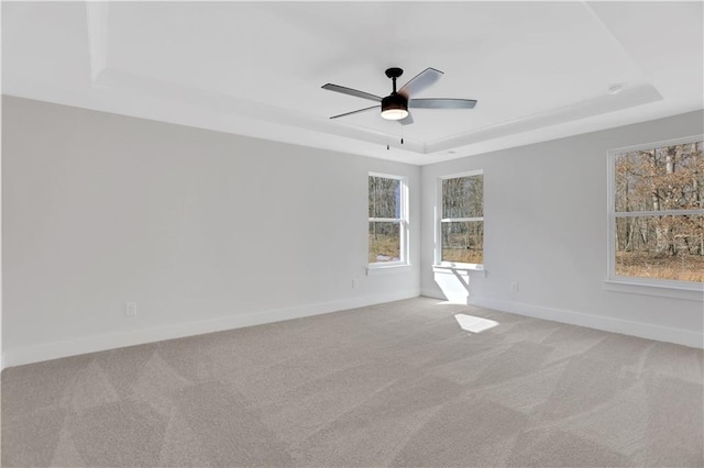 carpeted empty room with ceiling fan and a tray ceiling