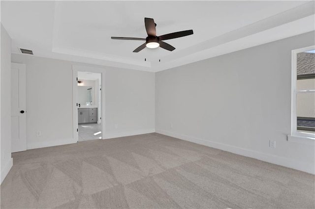 carpeted empty room with ceiling fan and a tray ceiling