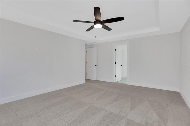 carpeted spare room featuring a raised ceiling and ceiling fan