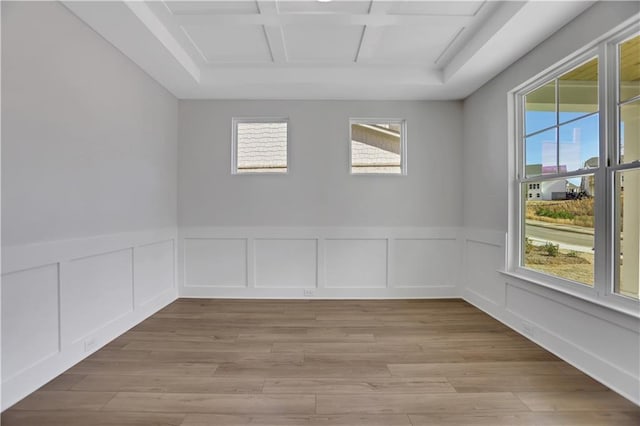 empty room featuring coffered ceiling and light hardwood / wood-style flooring